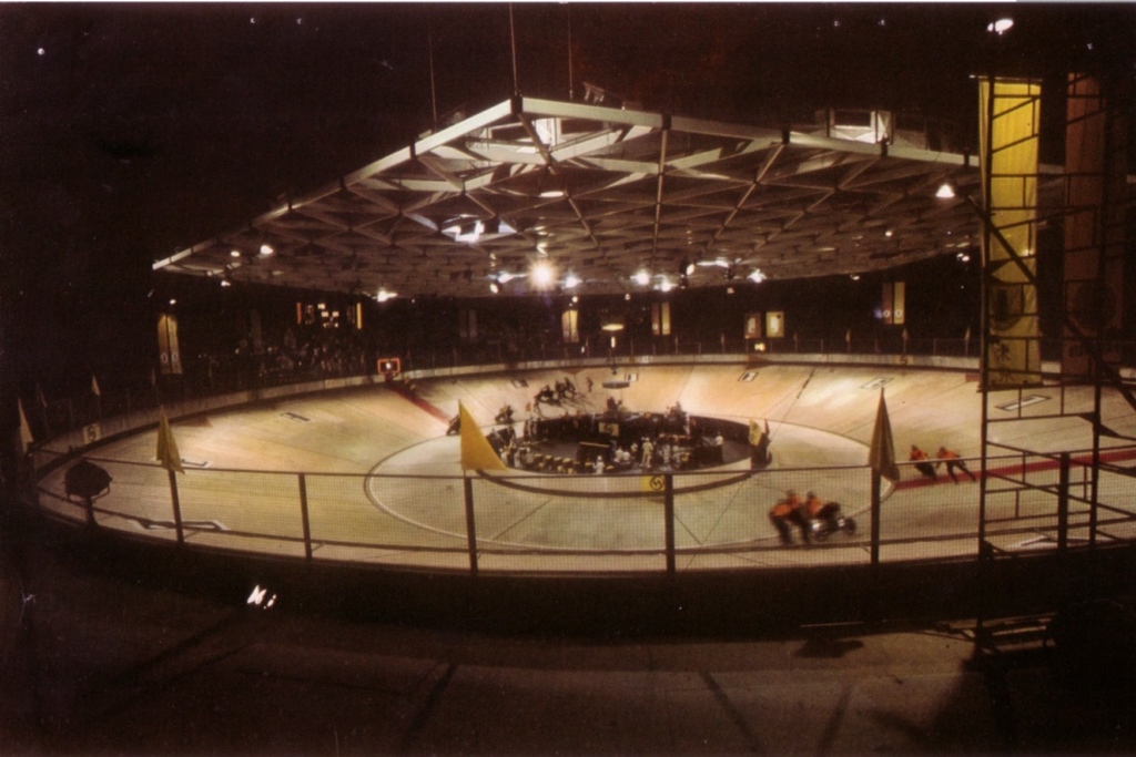 Rollerball's velodrome, a wide rink slanted inward with a metal ceiling and iris in the middle. 